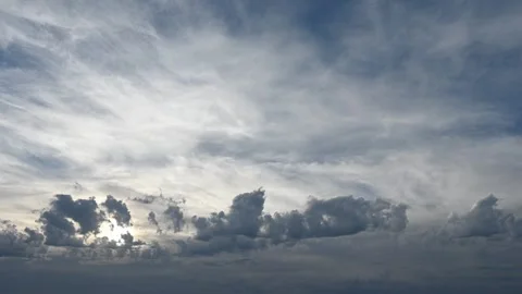 Time lapse of early morning backlit clouds blowing across a blue sky Stock Footage 296657181