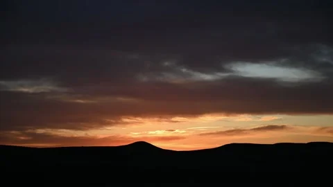 Time lapse of evening orange colored clouds after sunset above rolling hills Stock Footage 306541843