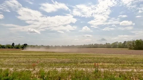 Time-lapse of a farmer in the distance plowing a field Stock Footage 179959765