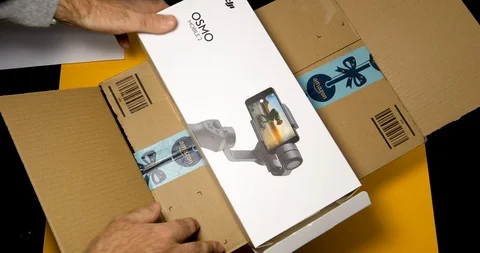 Time lapse, fast motion Man unboxing DJI Osmo 2 smartphone gimbal Video stock 100820867