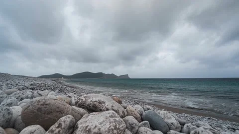 Time-Lapse fast moving rain clouds and waves on the stone coast of ibiza Video stock 176556630