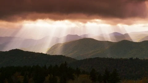 Time-lapse of fast moving sunrays falling mountains through the dark clouds Stock Footage 103395852