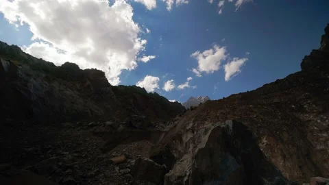 Time-lapse of floating clouds against blue sky over mountains or mountain. Video stock 218389124