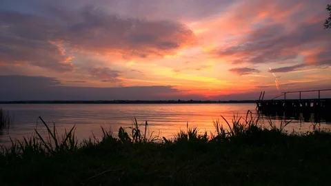 Time lapse  of flying clouds against the setting sun on the shore of a lake Stock Footage 105293578