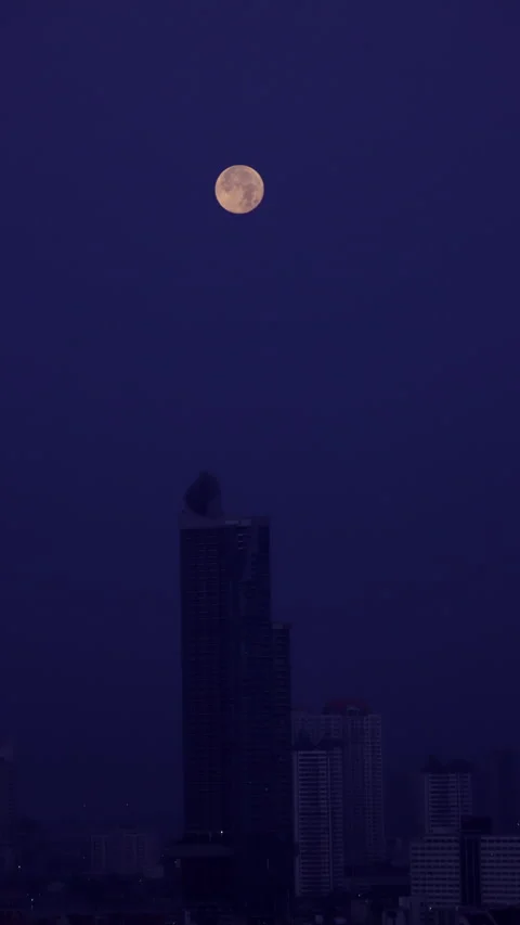 Time-lapse footage capturing the full moon setting behind tall city buildin.. Stockbeeldmateriaal 330886388