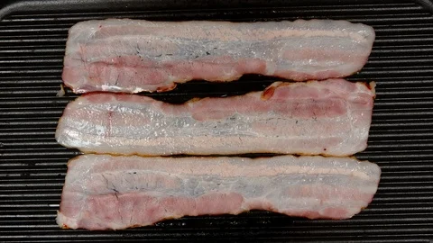 TIME-LAPSE: Frying a strips of bacon on a pan - Top view Stock Footage 125997647