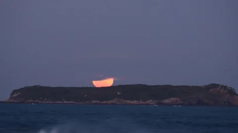 Time lapse of full moon rising behind an island 2K Stock Footage 89687376