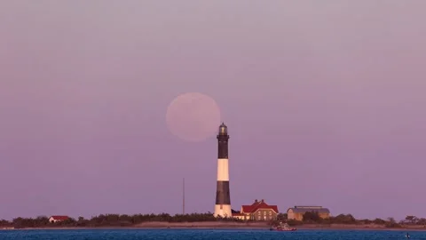 Time lapse of a full moon rising behind a tall stone lighthouse at sunset Stock Footage 153116667
