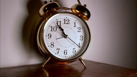 Time-Lapse of a Golden Vintage Clock on a Wooden Table in Low Light 動画素材 336257482