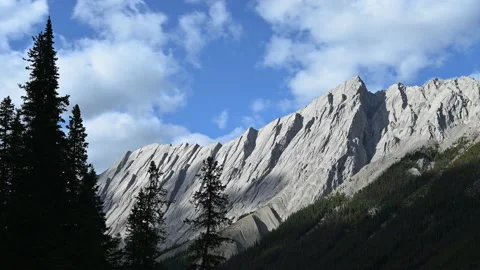 Time lapse of a gray mountain ridge with mid-day white clouds moving through a b Stock Footage 140937598