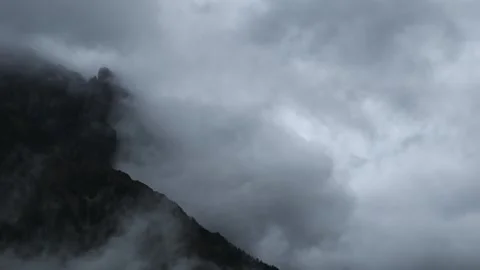 Time lapse of gray storm clouds blowing across a rocky mountain with distant tre Stock Footage 294256811