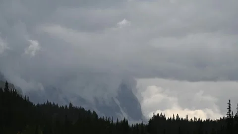 Time lapse of gray storm rain clouds above a forest next with rocky mountain in  Stock Footage 303380076