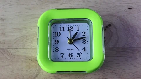 Time Lapse, green alarm clock with black numbers and arrows isolated on wooden Stock Footage 195001420