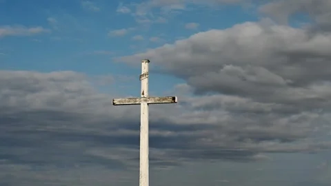 Time lapse of grey clouds in a light blue sky are moving above a large cross Stock Footage 280357442