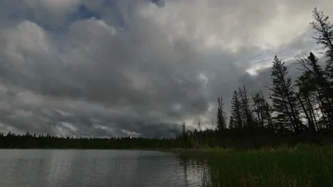 Time lapse of grey clouds moving over a small lake and reflecting in the water. Stock Footage 133090112