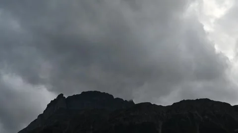 Time lapse of grey storm clouds blowing across the top of a rocky mountain ridge Stock Footage 303380004