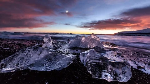 Time-lapse of ice bergs on the coast and clouds rolling in the sky at sunset Video stock 103814982