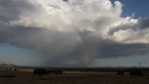 Time lapse of an isolated thunderstorm with a bright rainbow Stock Footage 247143780