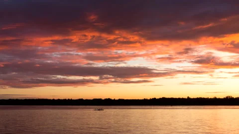 Time lapse of lake or river with moving silhouettes and cruise liner at sunset Stock Footage 168702350