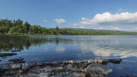 Time Lapse of Lake Shore Reflection with Rocks on Sunny Day in Ireland 動画素材 101607459