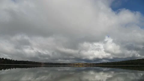 Time lapse of a large calm lake reflecting a complex cloudscape.  Stock Footage 140452488
