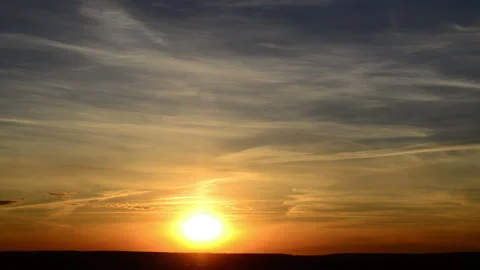 A time lapse of the large orange sunset as the massive sun sets into the horizon Stock Footage 131636856