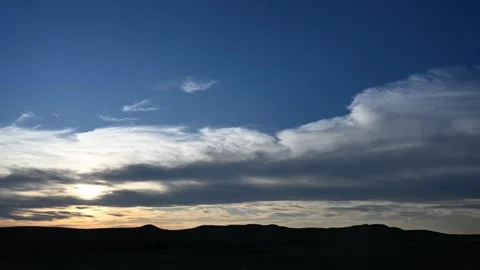 Time lapse of late day clouds in blue sky above a hilly silhouette setting Stock Footage 294256738