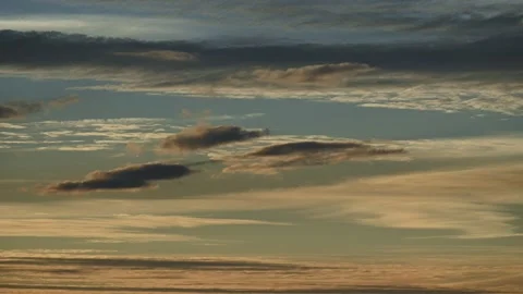 Time lapse of late day lens shaped clouds moving through a pale blue sky with su Stock Footage 300817652