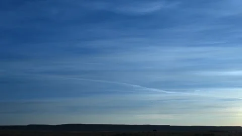 Time lapse of late day streaky clouds in a blue sky above a flat prairie land Stock Footage 289547914