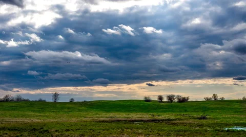 Time lapse layers of clouds moving over a green field Stock Footage 68823747