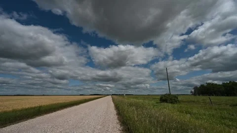 Time lapse looking down a gravel country road surrounded by agricultural fields  Stock Footage 247600610