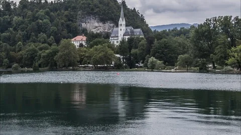 Time lapse low angle lake Bled with tourists walking on shore walkway Stock Footage 120990605