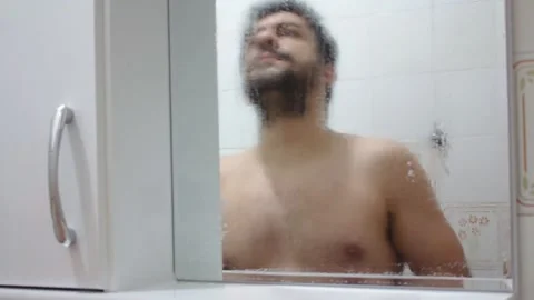 Time lapse of a man cleaning a bathroom mirror and shaving himself with a beard Vídeos de archivo 130980599
