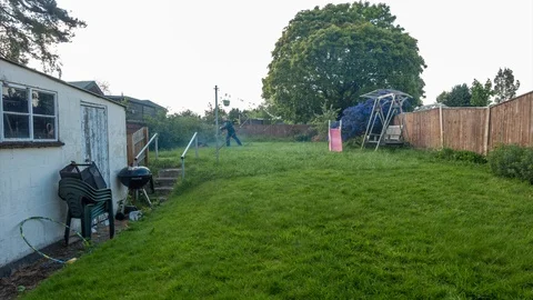 Time lapse of a man cutting a back lawn using a petrol lawnmower. Stock Footage 107913033
