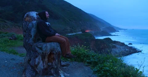 Time lapse of man sitting on a chair made of a dead tree in Big Sur, California. Stock Footage 72992496