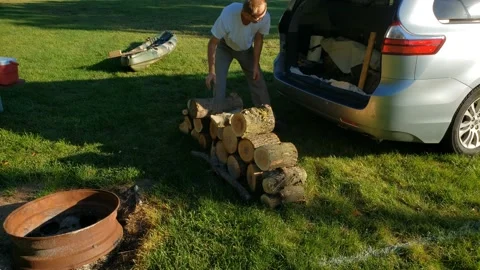 Time lapse of man stacking fire wood next to fire pit preparing camp site Stock Footage 139727711