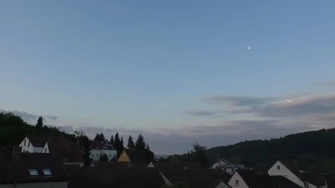 Time Lapse: Moon moving in the sky above rural village at sunrise Stock Footage 90624450
