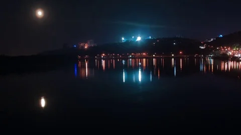 Time lapse. The moon rises above the night city. A boat sails on the river. Video stock 74264667
