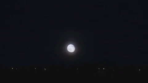 Time lapse of moon rising above row of houses and street lights Stock Footage 74749449