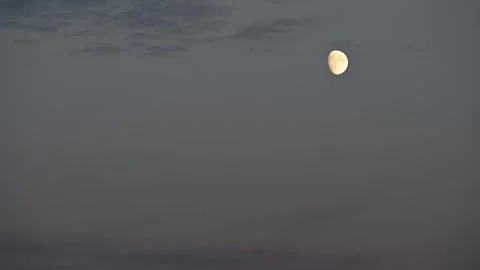 Time lapse of moon rising with moving thin gray clouds. Sky is pale bluish gray. Stock Footage 288011743