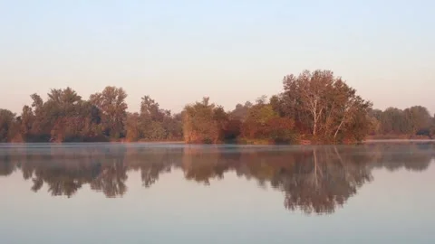 Time lapse of morning light on trees over foggy lake. 4K Video stock 319075963