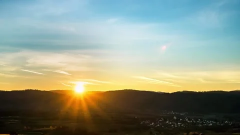 Time-lapse of mountain and village in morning, dramatic sky at sunrise Stock Footage
