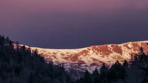 Time lapse of a mountain cliff covered with snow at sunset Stock Footage 233839669