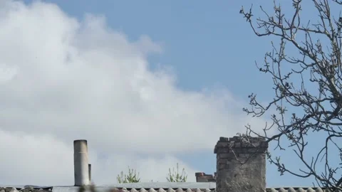 Time lapse of the movement of white clouds in the sky over an old roof with 스톡 동영상 238987769