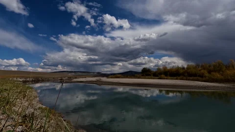 Time lapse of moving clouds over the river. Flowing water with mountains in.. Stock Footage 229438094