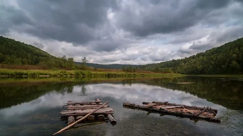 Time lapse of moving gray clouds reflecting on lake surrounded by a mountain Video stock 75835598