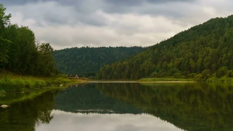Time lapse of moving gray clouds reflecting on lake surrounded by a mountain Stock Footage 75835872