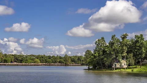Time lapse of moving white clouds over a lake, view of small cottage by the lake Stock Footage 218453034