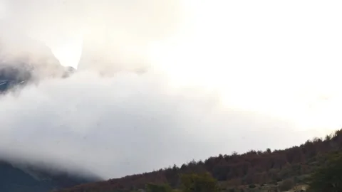 Time lapse of moving white clouds hiding and showing the top of mountains and Stock Footage 264758914