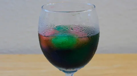 Time Lapse of Multi Colored Ice Coalescing in Wine Glass Stock Footage 1204658